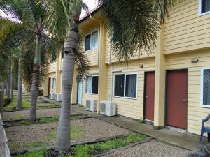 ein gelbes Gebäude mit Palmen davor in der Unterkunft TI Motel Torres Strait in Thursday Island