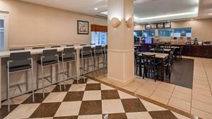 ein Restaurant mit einer Bar sowie Tischen und Stühlen in der Unterkunft Best Western Bar Harbour Inn in Massapequa Park