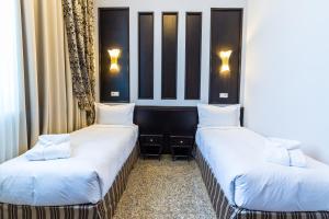 two beds in a hotel room with white sheets at Royal Petrol Hotel in Taldykorgan