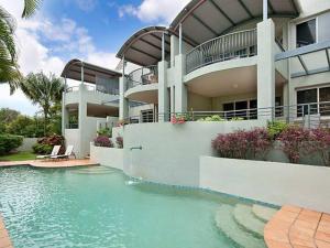 a building with a swimming pool in front of a house at Byron Beaches Location in Byron Bay