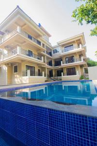 a house with a swimming pool in front of it at Woodside Retreat- Serviced Apartments in Baga