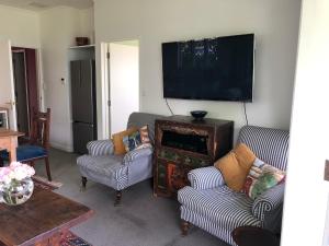 a living room with two chairs and a flat screen tv at Te Kopura Lodge in Martinborough