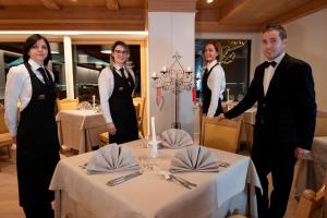 a group of people standing around a table in a restaurant at La Roccia Wellness Hotel in Cavalese