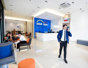 Hop Inn Hotel Tomas Morato Quezon City في مانيلا: رجل في بدلة يتحدث على الهاتف في بهو الفندق