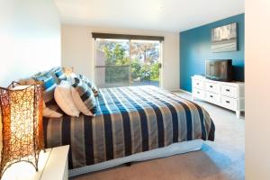 a bedroom with a bed and a window and a television at Pure Indulgence in Merimbula