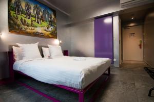 a bedroom with a large white bed with a painting on the wall at JJ32 in Luxembourg