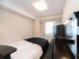 a hotel room with a bed and a flat screen tv at APA Hotel Kyoto Ekikita in Kyoto