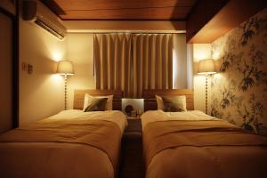 two beds in a hotel room with two lamps at Naha Southerlies Condominium Kumoji in Makishimachi