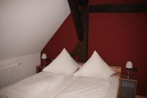 a bedroom with a bed with white sheets and pillows at Wirtshaus am Markt in Markt Nordheim