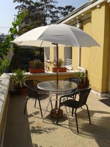 una mesa y sillas bajo una sombrilla en un patio en Hotel Las Flores, en Santiago