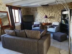 a living room with a couch and a tv at Gîte de l ancienne Poste in Bourdic