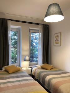 duas camas num quarto com duas janelas em A Place Like Home Apartamenty Wiewiorcza em Gdansk
