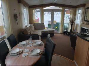a dining room table and chairs with plates and wine glasses at Park Home at Golden Sands Holiday Park in Foryd