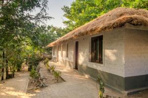 un petit bâtiment avec un toit de chaume et un sentier dans l'établissement Red Earth - Gokarna, à Ankola