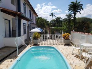 a swimming pool with a water fountain in a yard at Pousada das Hortensias in Conservatória