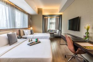 マニラにあるI'M Hotelのベッド2台とデスクが備わるホテルルームです。