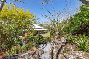 Casa con jardín con rocas y árboles en Deloraine Stone Cottage, en Whangarei
