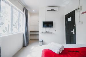 a bedroom with a red bed and a tv at RedDoorz @ Baloi Batam in Batam Center