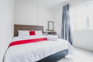 a white bedroom with a large bed with red pillows at RedDoorz @ Baloi Batam in Batam Center