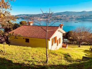 una pequeña casa en una colina con vistas al agua en Casa La Batea, en Aldán