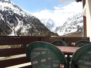 una mesa y sillas en un balcón con montañas cubiertas de nieve en Arolles 303, en Arolla