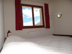 Un dormitorio con una cama blanca y una ventana. en Arolles 303, en Arolla