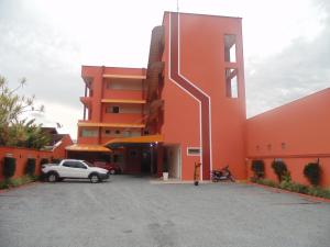 a orange building with a car parked in a parking lot at Hotel Jovilá in Jaraguá do Sul