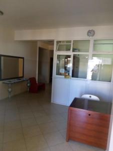a living room with a desk and a television at Restaurante Residencial Nova Cidade in Porto Novo