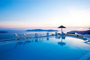 a swimming pool with chairs and a view of the ocean at Santorini Princess Spa Hotel in Imerovigli