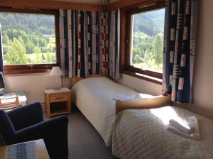 1 dormitorio con 2 camas, 1 silla y 2 ventanas en Smedsgården Hotel en Nesbyen
