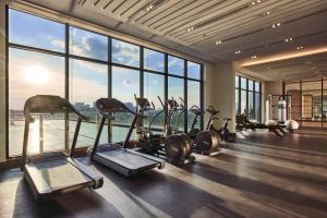 a gym with several treadmills and ellipticals in a room with windows at Oakwood Residence Saigon in Ho Chi Minh City