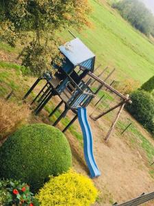 a wooden picnic table with a blue slide in a field at Hotel Wuelfers Gasthaus in Groß Ippener