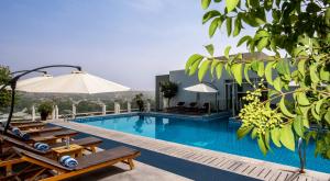 a pool at a hotel with chairs and an umbrella at Dushanbe Serena Hotel in Dushanbe