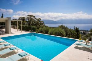 einen Pool mit Stühlen und Blick auf das Wasser in der Unterkunft Sterna Villa - Contemporary Villa with Private Pool & Sea Views, Fiskardo in Fiskardo