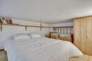 1 dormitorio con cama blanca y armario de madera en 3 people - Place des Vosges Paris by Weekome en París