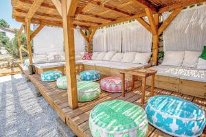 a wooden pergola with couches and chairs on a deck at ECO Aparthotel The Dreamers's Club in Lumbarda