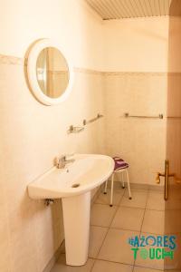 a white bathroom with a sink and a mirror at Hospedaria casa D'Avo in Praia da Vitória