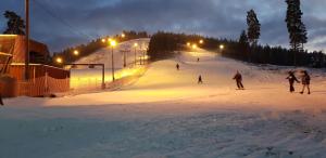 a group of people skiing down a ski slope at night at Hotell Monica in Hagfors