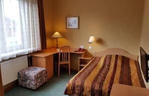 um quarto de hotel com uma cama, uma secretária e uma cadeira em Home B&B em Kaunas
