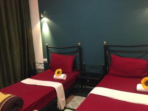 two twin beds in a room with red sheets and twoatoessenalsenal at Nobel Hotel in Amman