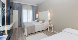 a hotel room with two beds and a television at Canyelles Platja in Roses