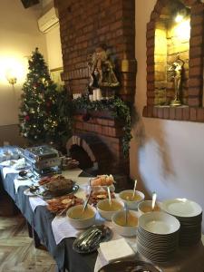 a long table with food on it with a christmas tree at Guest House Prenoćište Piccolina in Sombor