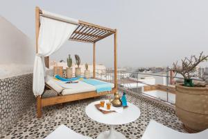 Habitación con cama y mesa en el balcón. en Riad Emotion, en Essaouira