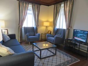 a living room with a blue couch and chairs and a tv at casAlice country house in Alvoeira