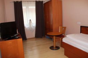 a bedroom with a bed and a table and a television at Heppenheimer Hof Hotel in Worms