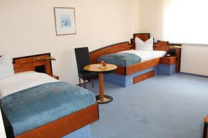 sypialnia z 2 łóżkami i małym stołem w obiekcie Heppenheimer Hof Hotel w Wormacji