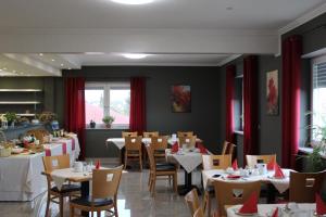 ein Esszimmer mit Tischen, Stühlen und roten Vorhängen in der Unterkunft Heppenheimer Hof Hotel in Worms
