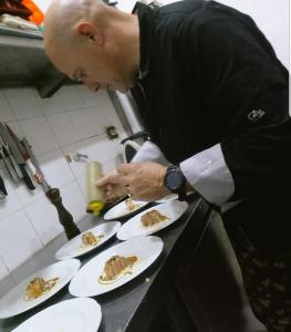 a chef preparing plates of food on a counter at Hotel Rural La Pampeana in Sarah