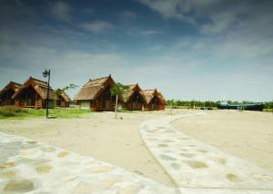 a row of wooden huts on a sandy beach at Dolphin Camping in Sfântu Gheorghe