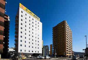 三原市Super Hotel Mihara Ekimae的一座高大的白色建筑，顶部有一块招牌